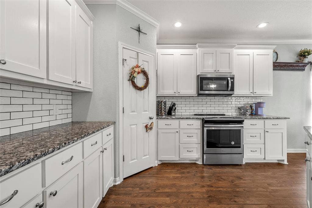 215 Greenbriar Street, Robinson, TX 76706 Kitchen featuring white shaker cabinetry, granite-style countertops, subway tile backsplash, stainless steel appliances, and wood-finish flooring