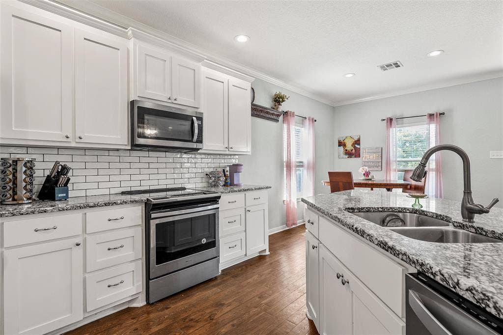 215 Greenbriar Street, Robinson, TX 76706 Modern kitchen featuring white cabinetry, granite countertops, and wood-finish flooring