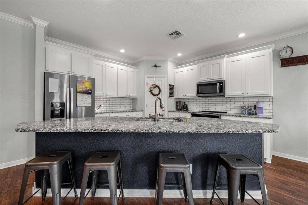 215 Greenbriar Street, Robinson, TX 76706 Kitchen featuring a large island with a durable countertop, white shaker cabinetry, stainless steel appliances, a subway tile backsplash, and recessed lighting