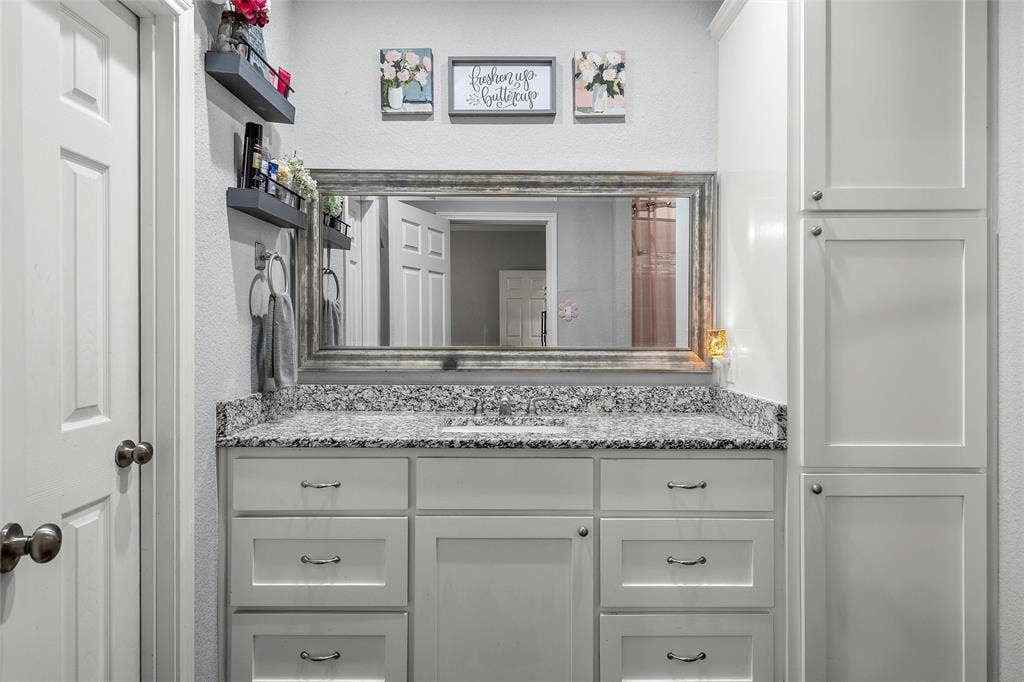 215 Greenbriar Street, Robinson, TX 76706 Bathroom vanity with a single basin, granite countertop, shaker-style cabinetry, and a full-width framed mirror