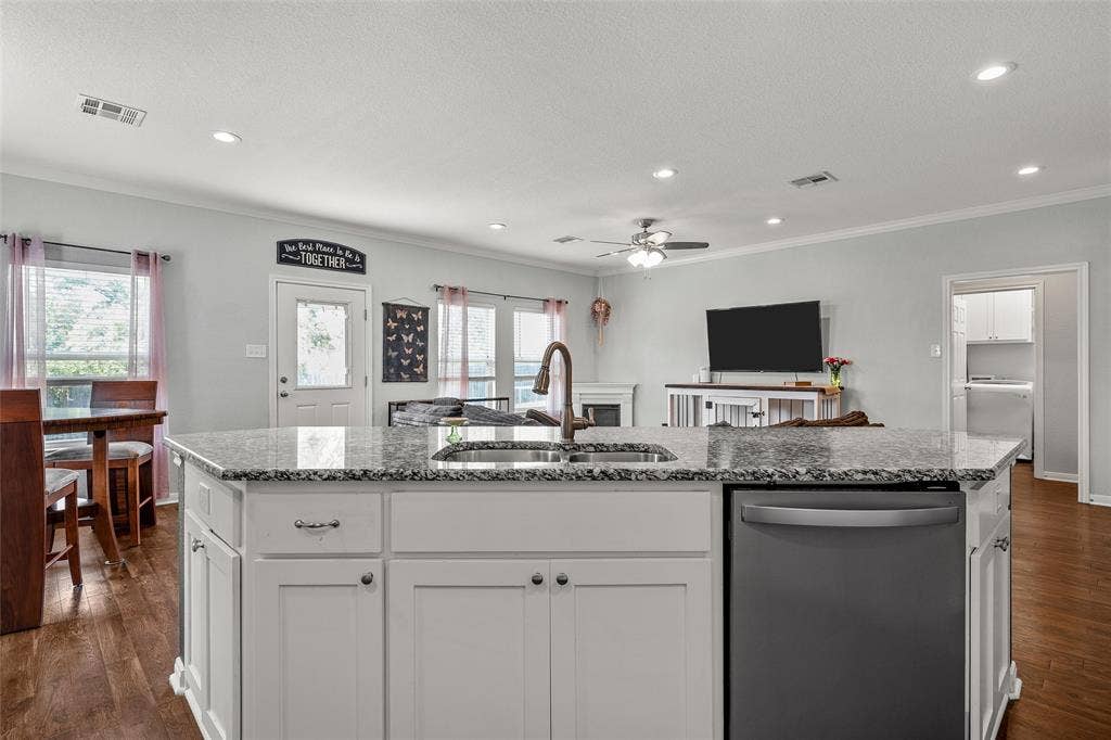 215 Greenbriar Street, Robinson, TX 76706 Kitchen island featuring a granite countertop, undermount sink, and integrated dishwasher