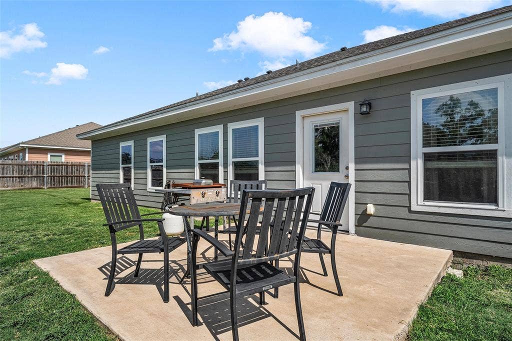 215 Greenbriar Street, Robinson, TX 76706 Rear exterior featuring a concrete patio, a white paneled door, and multiple windows with white trim
