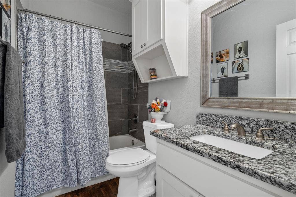 215 Greenbriar Street, Robinson, TX 76706 Bathroom featuring a white vanity with a dark speckled countertop, an undermount sink, and a framed mirror