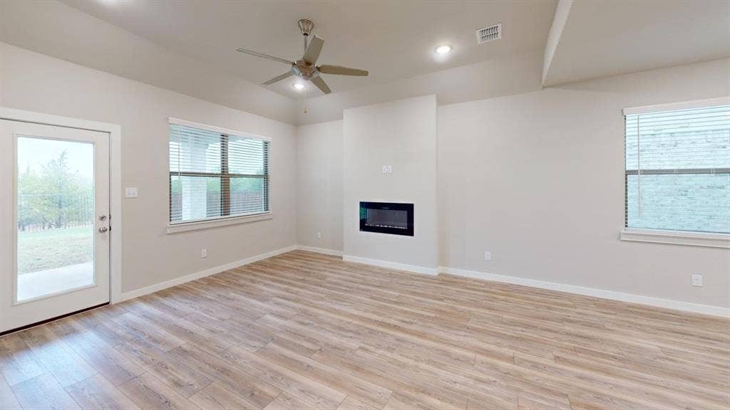 1323 Great Sand Dune Street, Royse City, TX 75189 Spacious living area featuring wood-finish flooring, a contemporary electric fireplace, and a ceiling fan