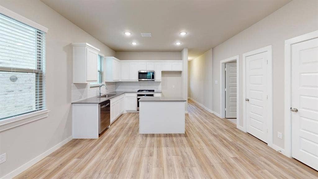 1323 Great Sand Dune Street, Royse City, TX 75189 Open-concept kitchen with a central island, recessed lighting, white cabinetry, stainless steel appliances, and light wood-finish flooring