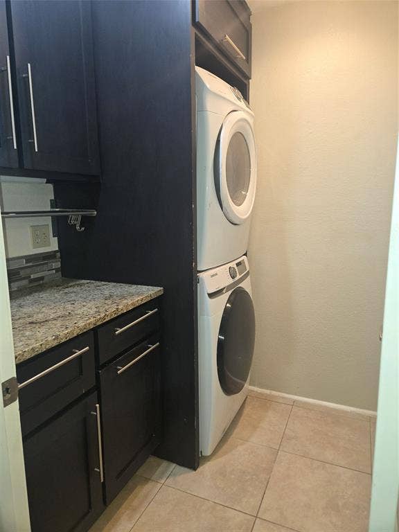 1402 Signet Drive, Euless, TX 76040 Laundry area featuring dark cabinetry, speckled countertop, tiled backsplash, and light-toned floor tiles