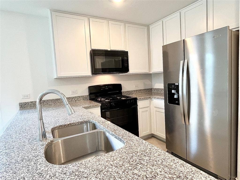 7212 Gray Wolf Lane, McKinney, TX 75071 Kitchen featuring black appliances, white cabinets, and light stone counters