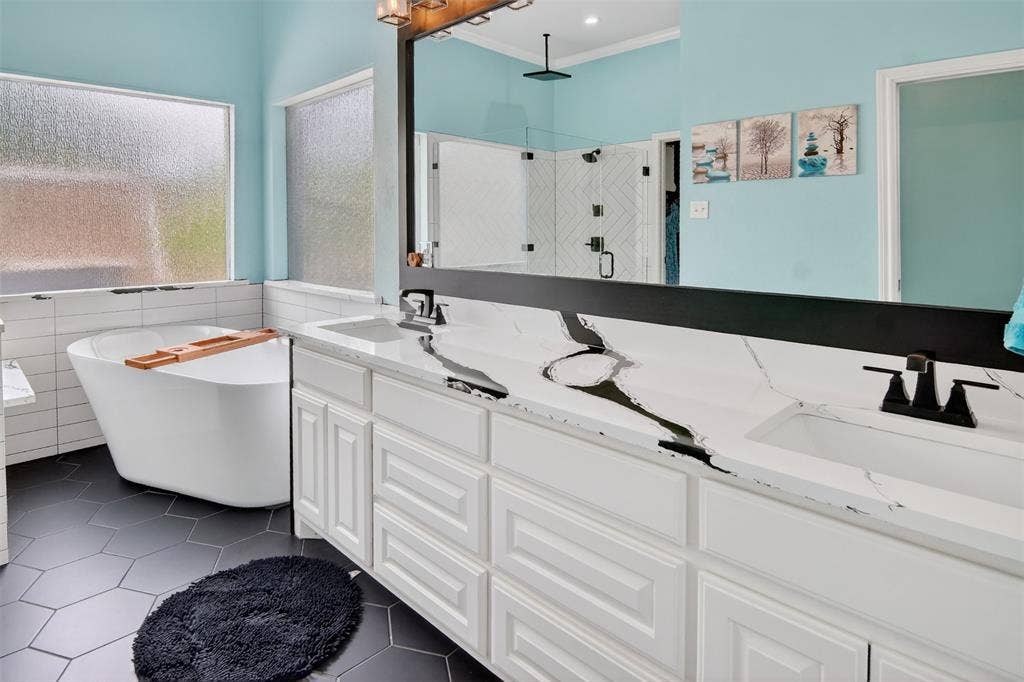 1202 Forest Park Drive, Weatherford, TX 76087 Lovely ensuite bathroom with dual sinks, large framed mirror, free-standing soaking tub, and lots of natural light.