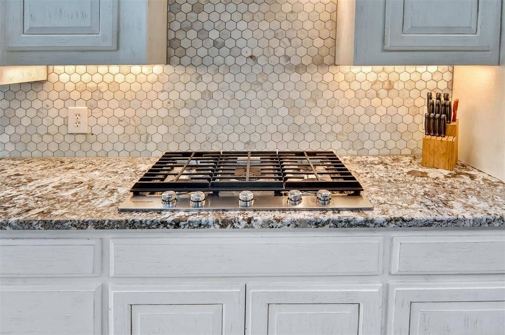 1202 Forest Park Drive, Weatherford, TX 76087 Five burner gas cooktop, granite counters, tile backsplash, and under cabinet lighting.