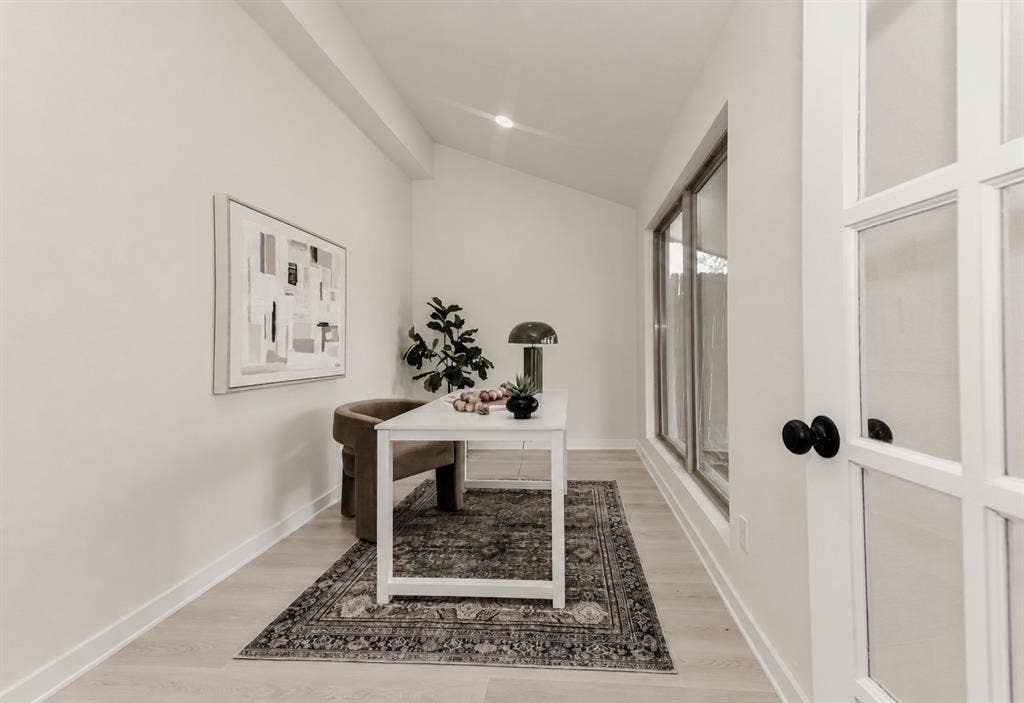 The office area has an expansive window array, wood-finish flooring, and a glass-paned door with black hardware