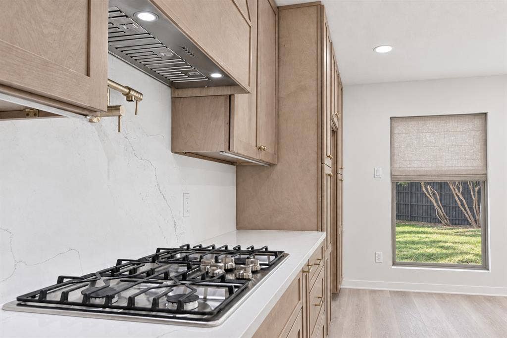 Built-in gas cooktop with stainless steel range hood will delight any Chef