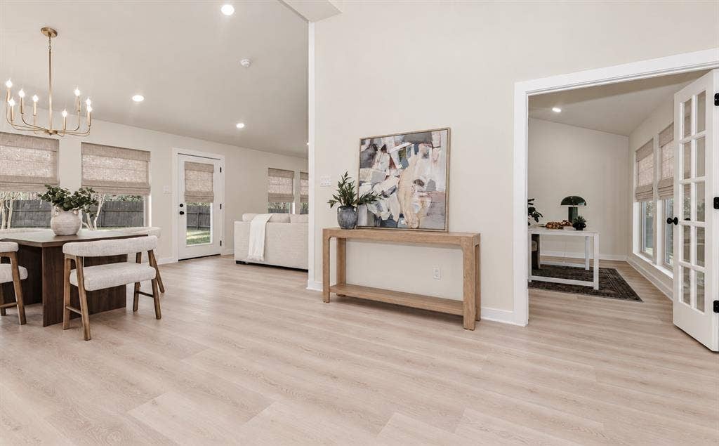 Light wood-finish flooring throughout, vaulted ceilings, recessed lighting, and French doors create an open feeling