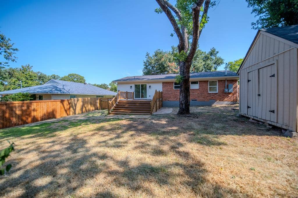 Expansive backyard featuring a multi-level wood deck with steps, a wood privacy fence, and a detached storage shed