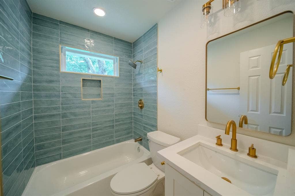 Bathroom featuring a built-in tub with a tile surround, recessed shelf, and transom window