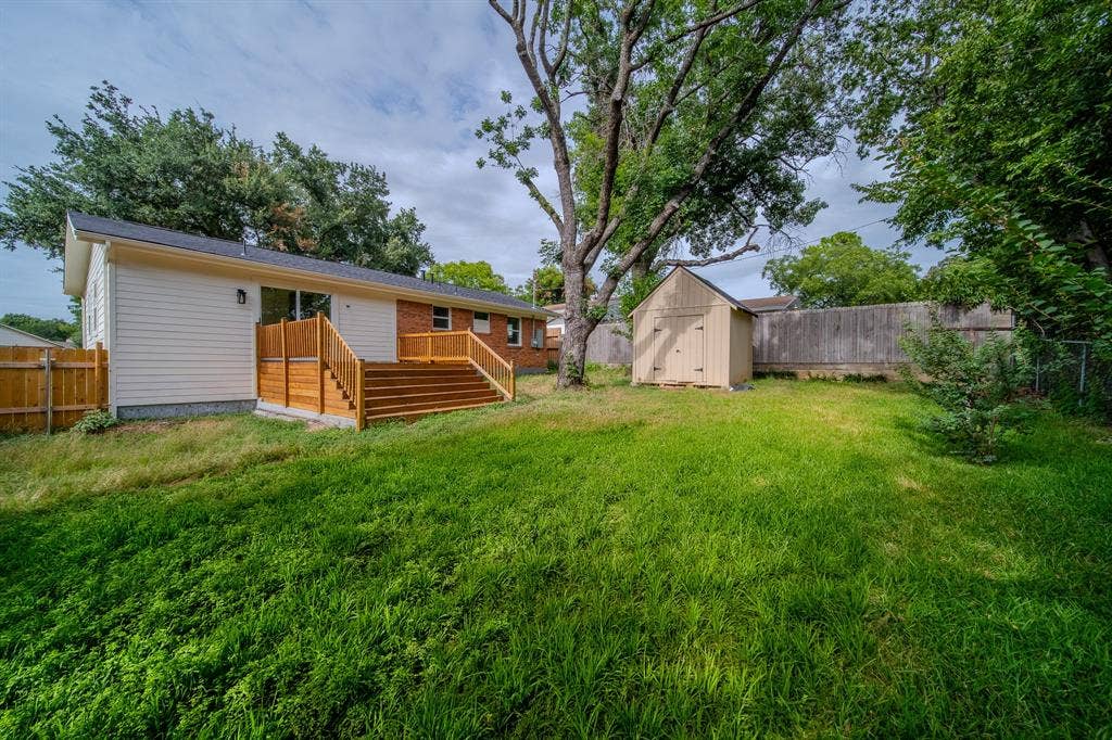 Expansive green lawn with mature trees and a private wooden fence
