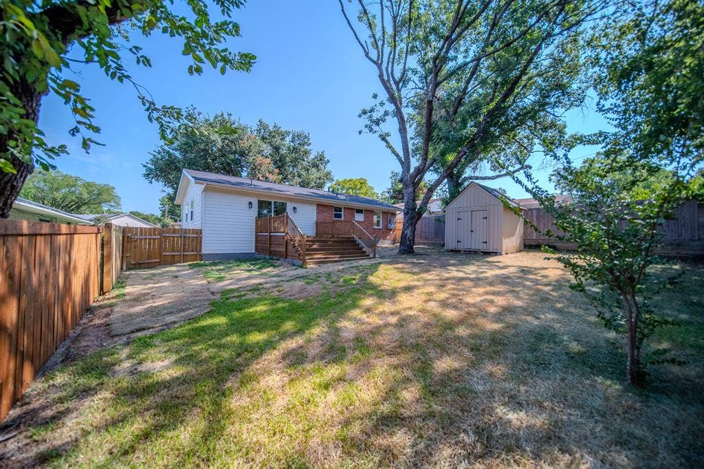 Private backyard featuring a wood privacy fence, mature trees, a multi-level wood deck, and a detached storage shed