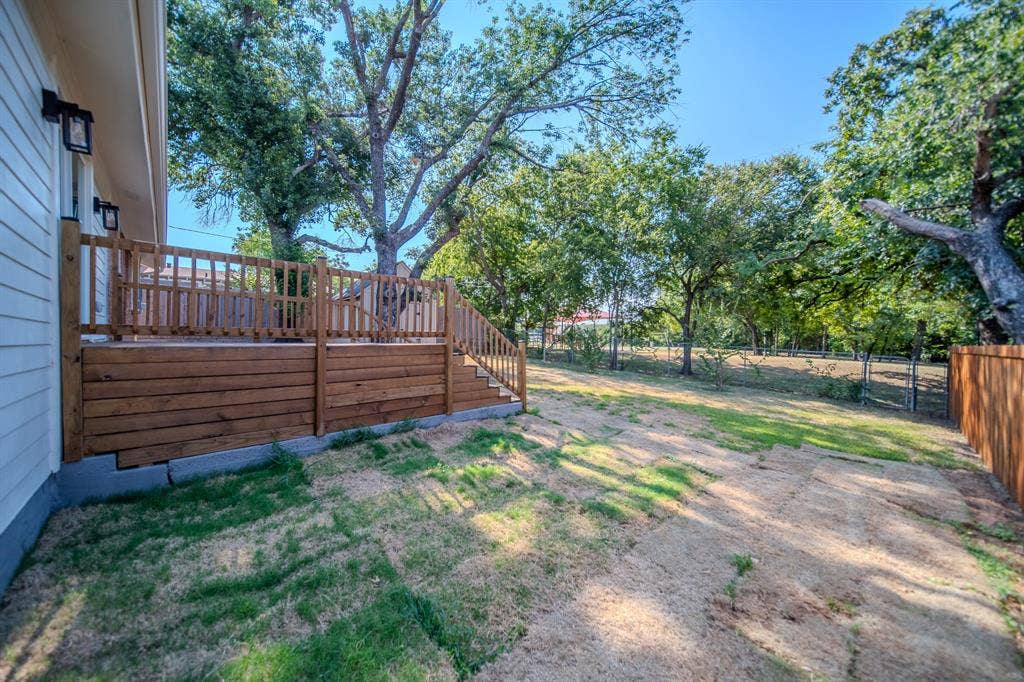 Wooden deck featuring a railing and steps, with mature trees providing a natural canopy