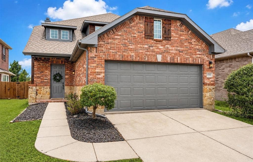 1709 Belton Drive, Prosper, TX 75078 Brick and stone exterior featuring a gray garage door, a concrete driveway, and a concrete walkway leading to the front entry