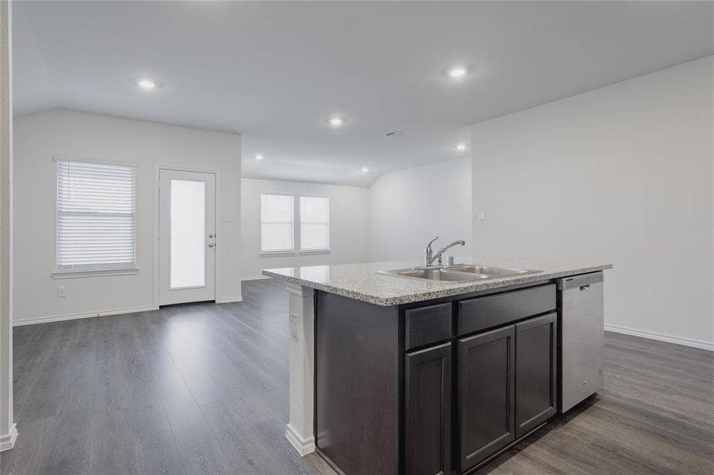 2904 Goodrich Street, Royse City, TX 75189 Kitchen island featuring a double-basin stainless steel sink, granite-style countertop, and integrated dishwasher