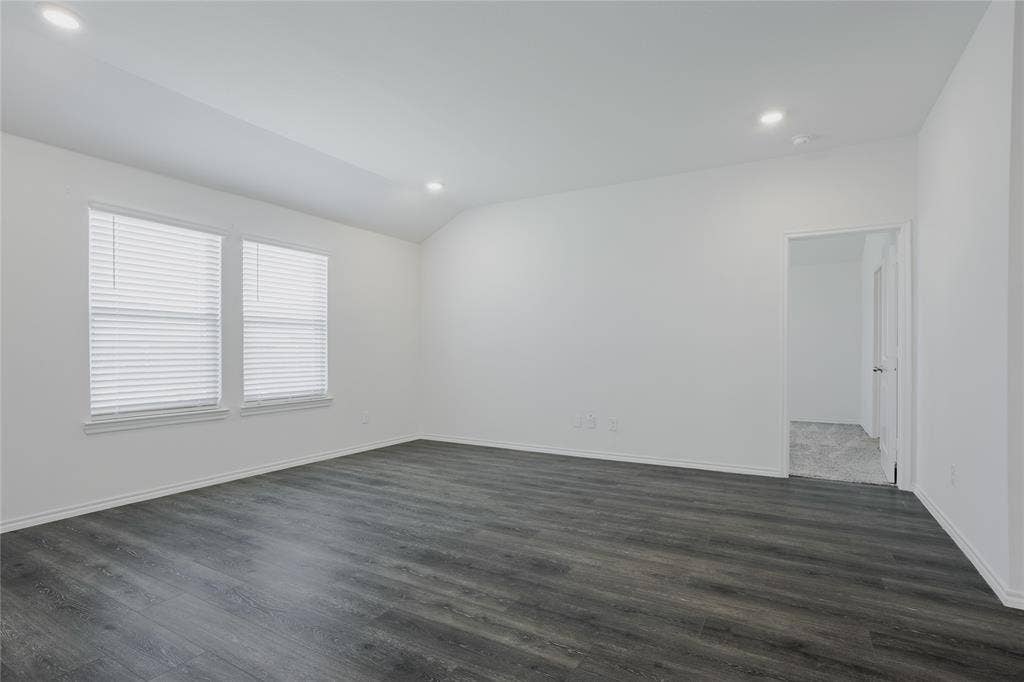 2904 Goodrich Street, Royse City, TX 75189 Spacious room featuring dark wood-finish flooring, two windows with blinds, recessed lighting, and white walls