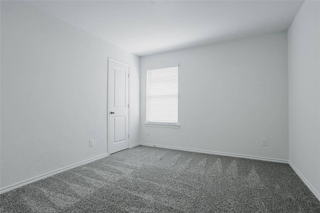 2904 Goodrich Street, Royse City, TX 75189 Neutral-toned room featuring a single window with blinds, light gray textured walls, and a gray patterned carpet