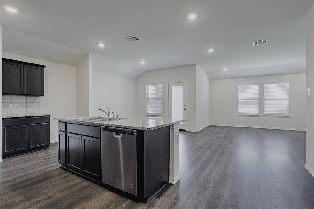 2904 Goodrich Street, Royse City, TX 75189 Kitchen island featuring an integrated sink, stainless steel dishwasher, and granite countertop