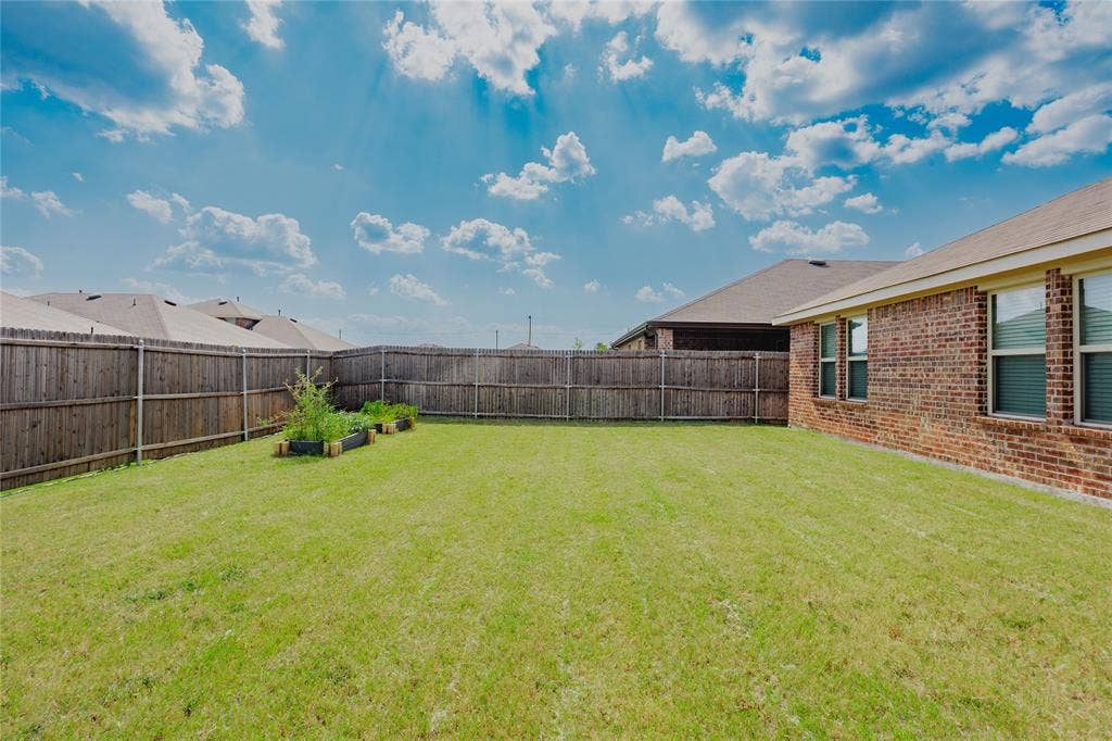 2904 Goodrich Street, Royse City, TX 75189 Expansive backyard featuring a green lawn, wood privacy fencing, and raised garden beds