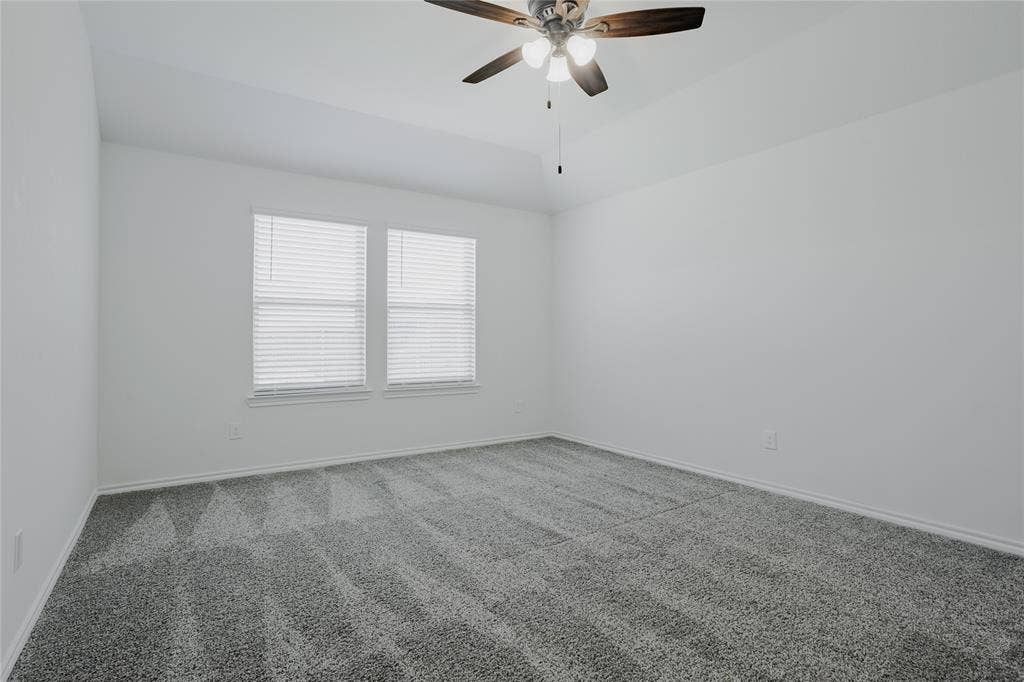 2904 Goodrich Street, Royse City, TX 75189 Spacious room featuring neutral carpeting, a ceiling fan with integrated lighting, two windows with blinds, and white painted walls