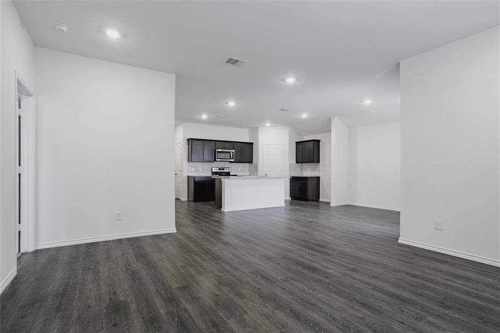 2904 Goodrich Street, Royse City, TX 75189 Open-concept interior featuring dark wood-finish flooring, recessed lighting, and a kitchen with dark cabinetry and stainless steel appliances