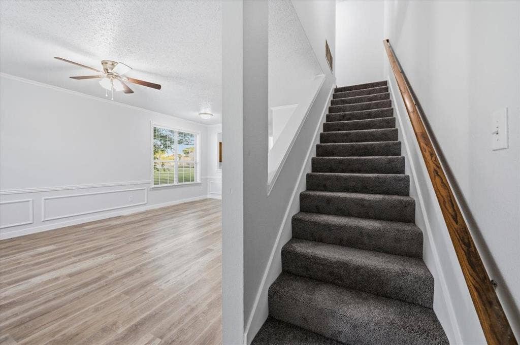 2122 W E Roberts Drive, Grand Prairie, TX 75051 Staircase with gray carpeted treads and a wooden handrail