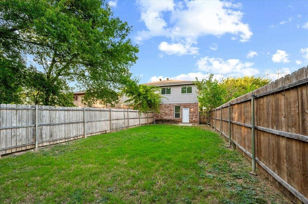 2122 W E Roberts Drive, Grand Prairie, TX 75051 Private backyard featuring a manicured lawn, established trees, and a full perimeter wood fence