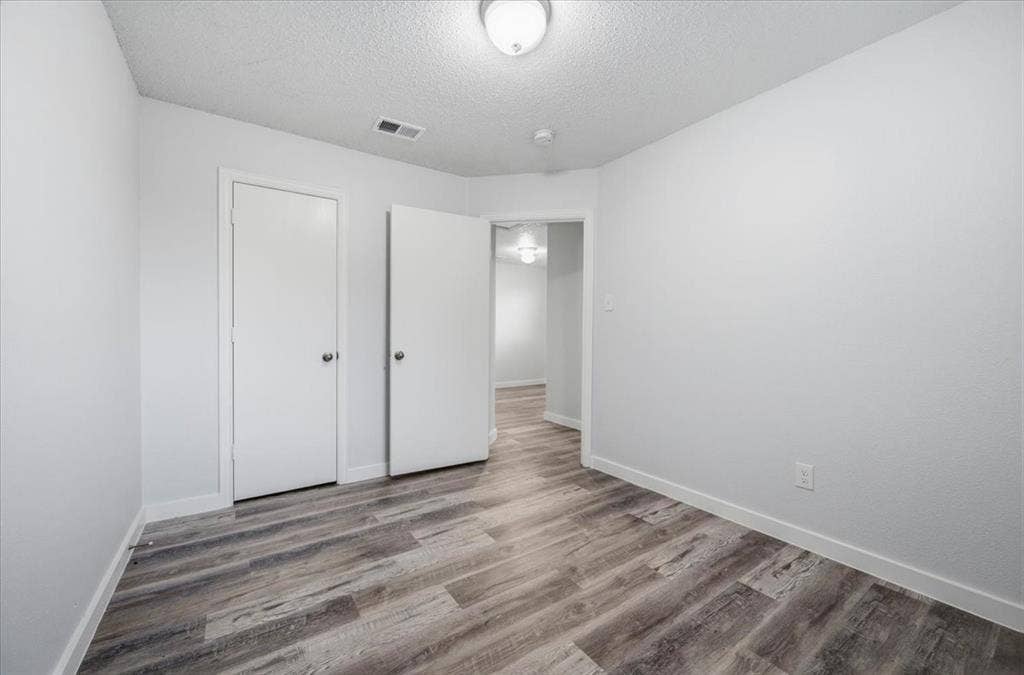 2122 W E Roberts Drive, Grand Prairie, TX 75051 Room featuring wood-finish flooring, two white doors, white baseboards, and a flush mount ceiling light