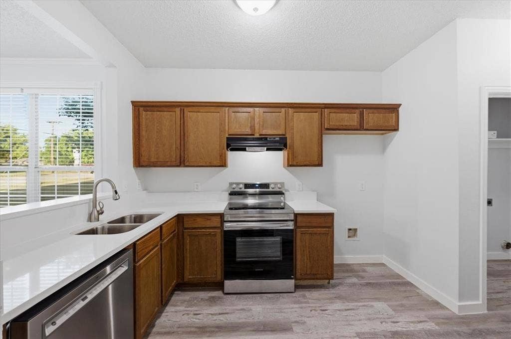 2122 W E Roberts Drive, Grand Prairie, TX 75051 Kitchen featuring wood cabinetry, stainless steel appliances, white countertops, and wood-finish flooring