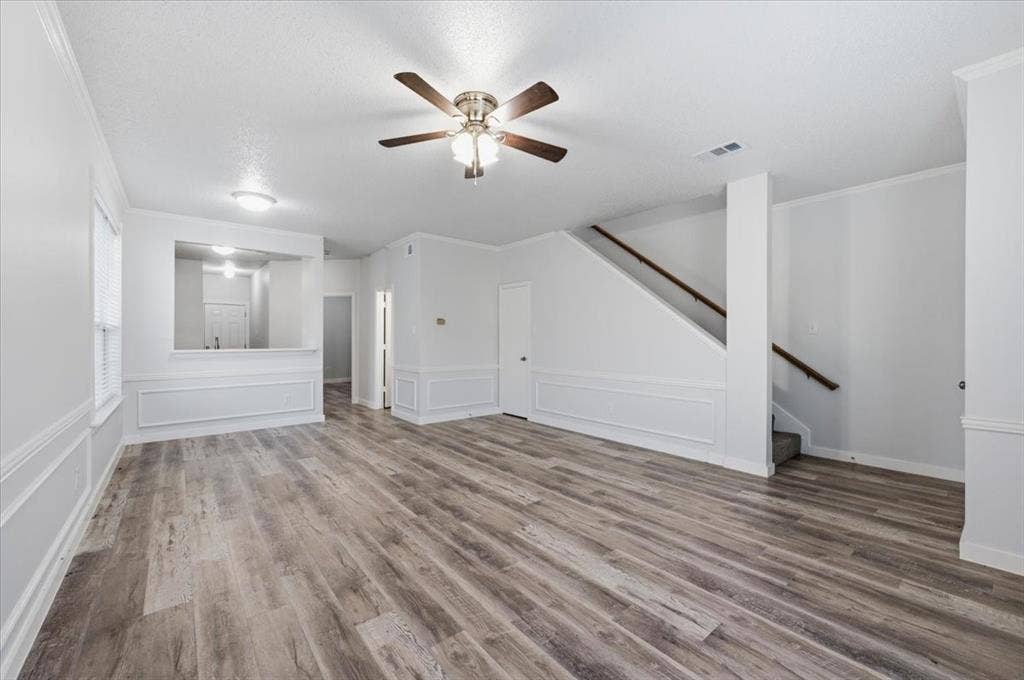 2122 W E Roberts Drive, Grand Prairie, TX 75051 Spacious living area featuring wood-finish flooring, a ceiling fan with integrated lighting, and white wainscoting