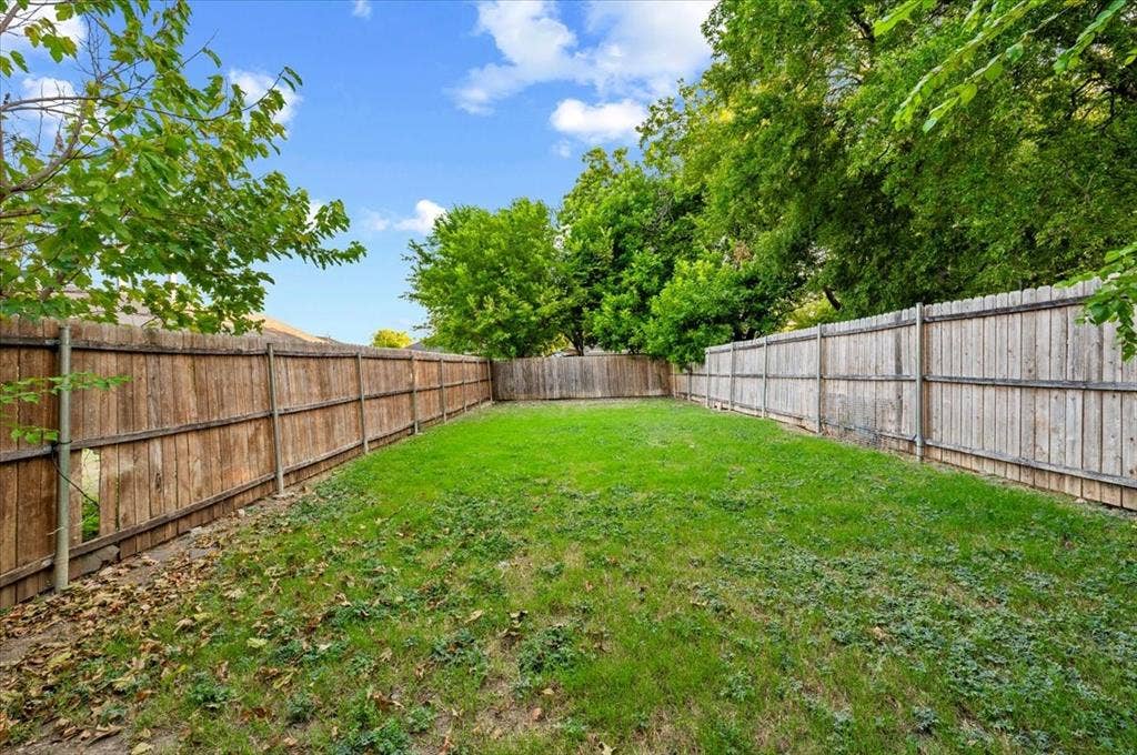 2122 W E Roberts Drive, Grand Prairie, TX 75051 Spacious backyard featuring a grass lawn and wood-panel perimeter fencing