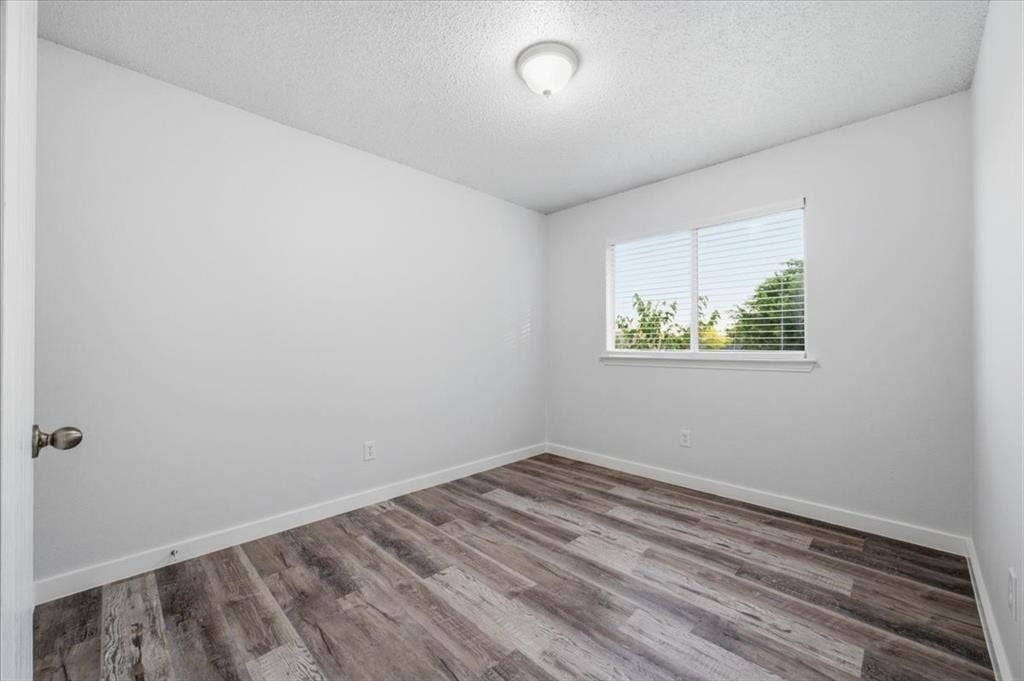 2122 W E Roberts Drive, Grand Prairie, TX 75051 Room featuring wood-finish flooring, a window with blinds, and a ceiling-mounted light fixture