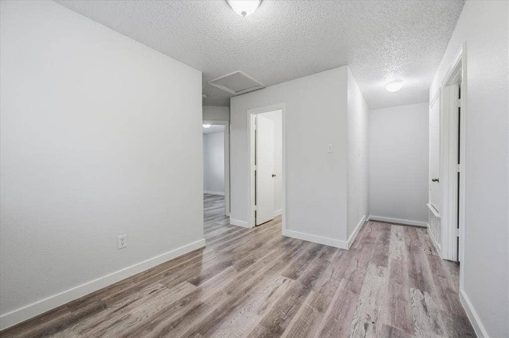 2122 W E Roberts Drive, Grand Prairie, TX 75051 Open interior space featuring wood-finish flooring, white walls, and bright overhead lighting