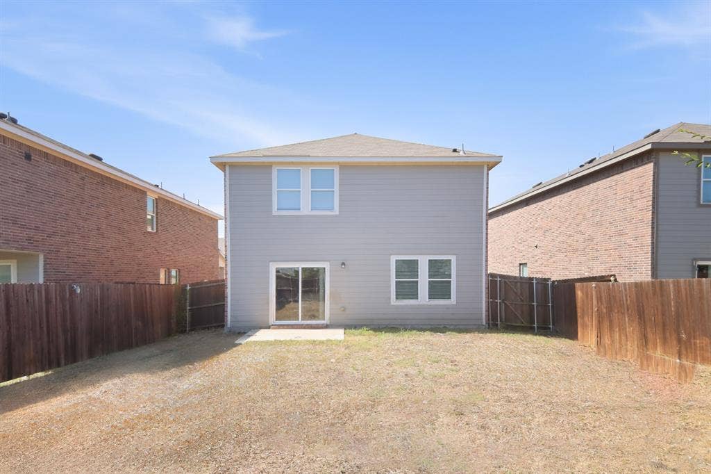 6520 Calico Lane, Forney, TX 75126 Rear exterior featuring light gray siding, white-framed windows, and a sliding glass door