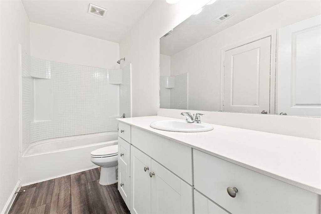 6520 Calico Lane, Forney, TX 75126 Bathroom featuring a white vanity with integrated sink, white countertop, and wood-finish flooring