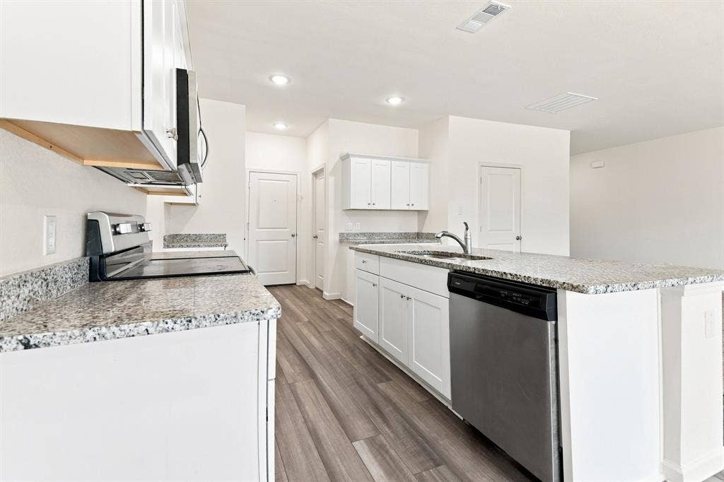 6520 Calico Lane, Forney, TX 75126 Modern kitchen featuring white cabinetry, granite countertops, stainless steel appliances, a kitchen island with a sink, and wood-finish flooring