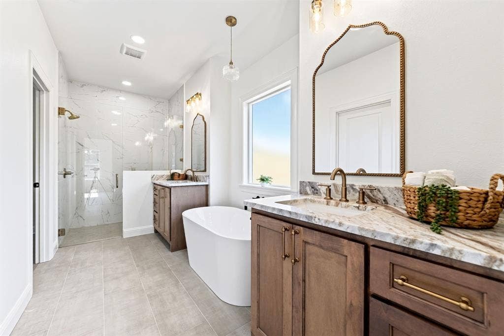 Primary en-suite featuring marble tile in the walk in shower, dual vanities with ample space for to get ready for a day of errands or a night out on the town.
