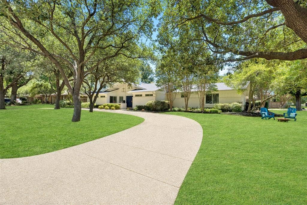 4110 Shady Hill Drive, Dallas, TX 75229 A sweeping circular drive winds beneath mature trees, creating an inviting approach to this beautifully landscaped home.