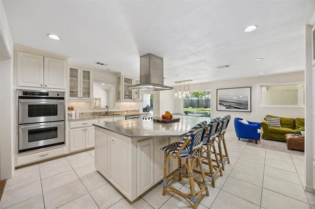 4110 Shady Hill Drive, Dallas, TX 75229 Spacious kitchen centers around an oversized island with seating, double ovens, abundant cabinetry, and an open connection to the casual living and dining areas.