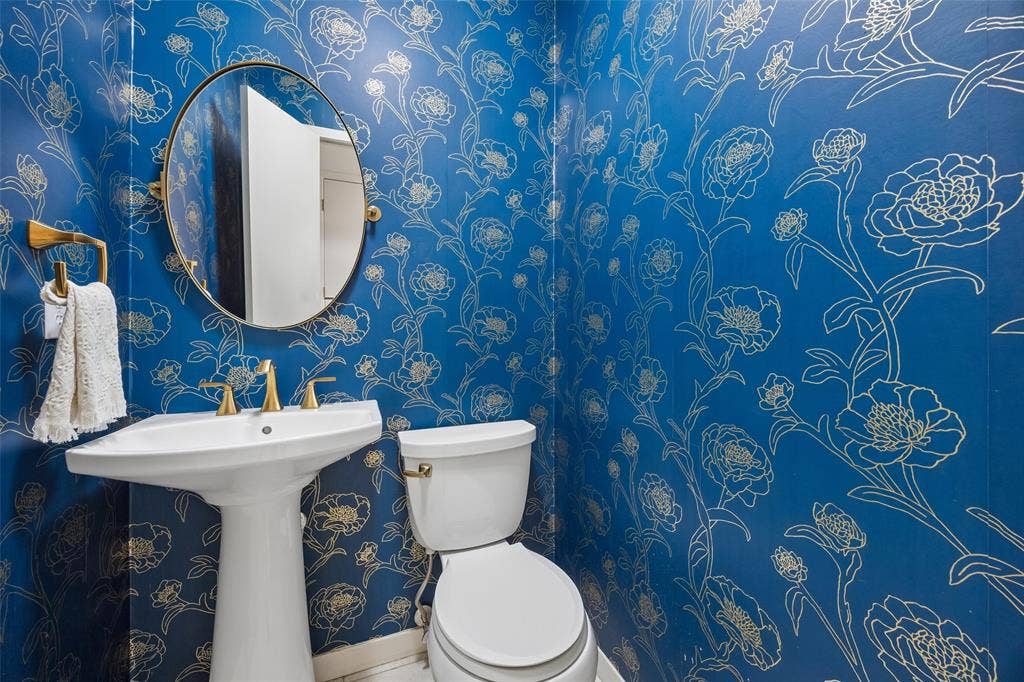 4110 Shady Hill Drive, Dallas, TX 75229 A stylish powder bath makes a bold statement with vibrant floral wallcovering and warm brass accents.