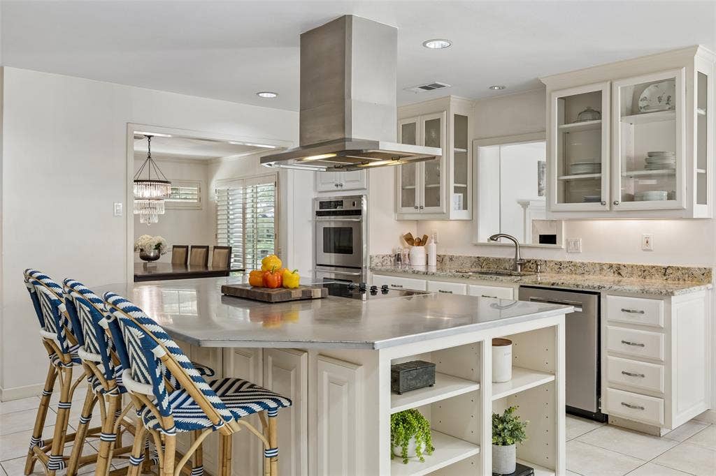4110 Shady Hill Drive, Dallas, TX 75229 A closer view of the kitchen highlights the oversized island with seating, generous storage, glass-front cabinetry, and sleek stainless steel vent hood.