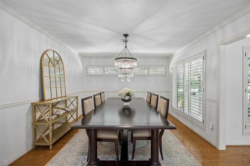4110 Shady Hill Drive, Dallas, TX 75229 Formal dining room featuring wood flooring, plantation shutters, elegant millwork and a striking statement chandelier.