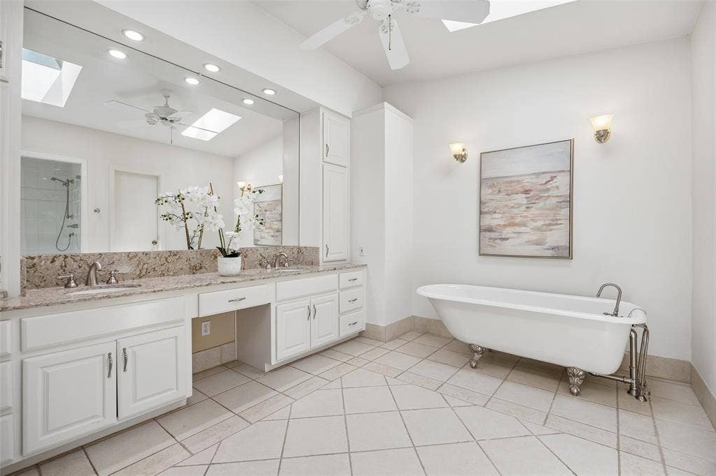 4110 Shady Hill Drive, Dallas, TX 75229 The spacious primary bathroom with a freestanding soaking tub, dual vanities, frameless shower, abundant storage, and skylights that fill the space with natural light.