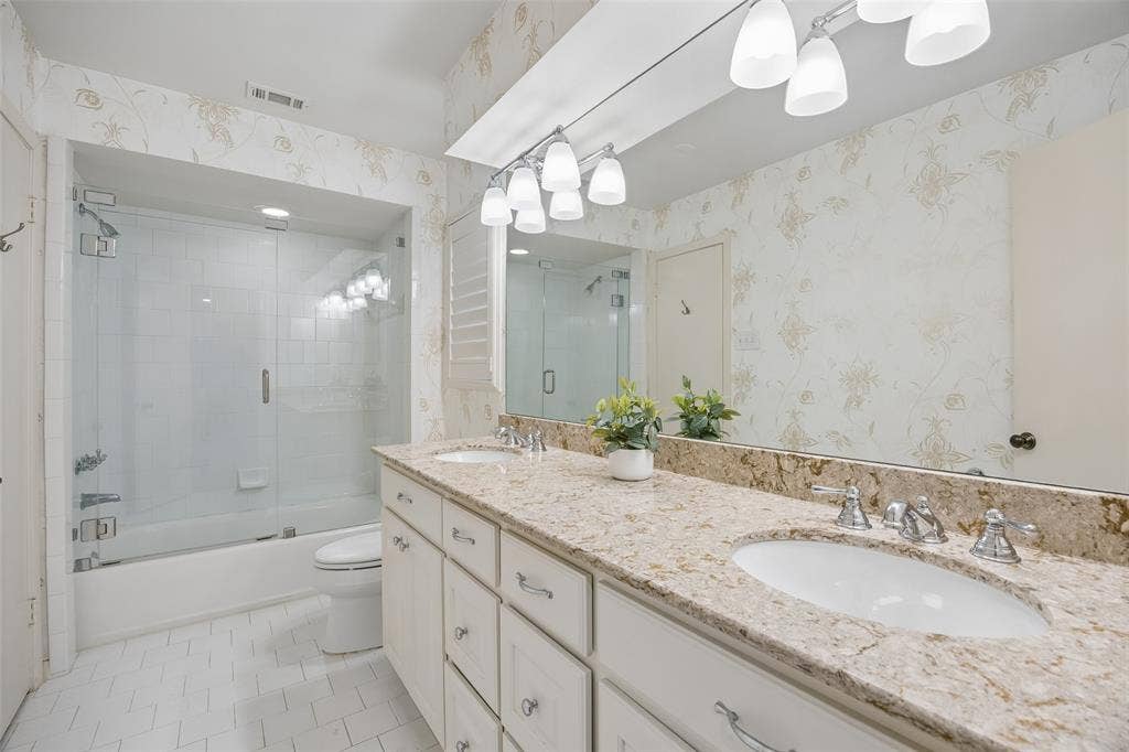 4110 Shady Hill Drive, Dallas, TX 75229 The downstairs Jack-and-Jill bath features dual sinks, a generous vanity and a tub-shower combination with frameless glass.