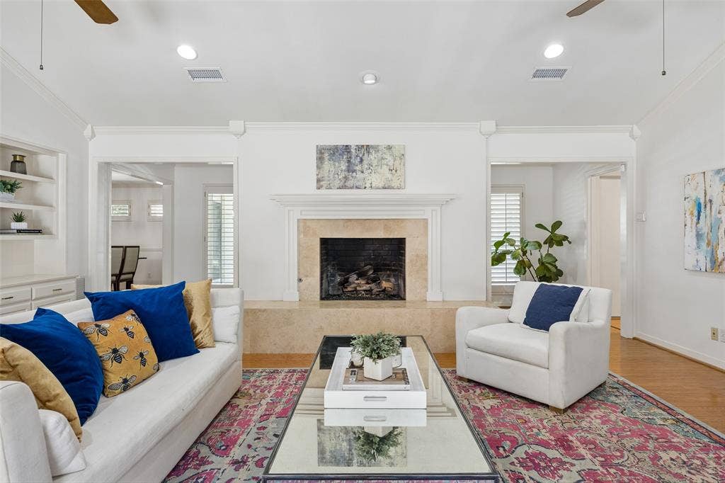 4110 Shady Hill Drive, Dallas, TX 75229 Located in the center of the home. The living room is anchored by a classic fireplace and features built-in shelving, wood floors, and a bright, open feel.