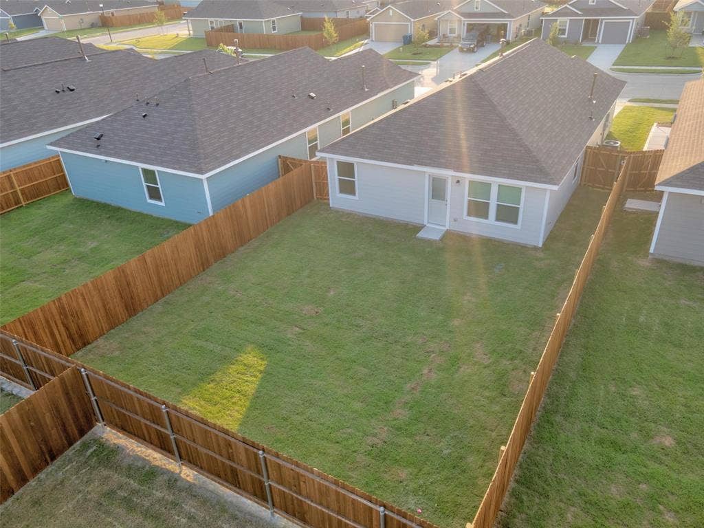 6005 Determine Lane, Forney, TX 75126 Spacious, fenced backyard featuring a manicured lawn, light gray exterior siding, white trim, a rear entry door, and multiple windows